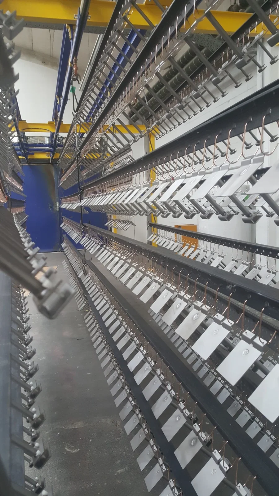 Pulverbeschichtungsanlage mit aufgehängten Industriebauteilen in Serienfertigung